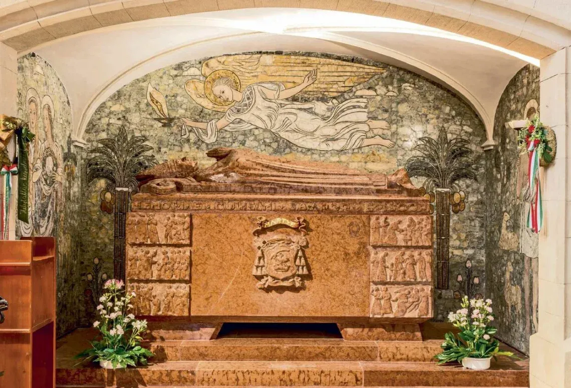 Vilmos Apor’s tomb in the cathedral basilica of Győr. The red marble tomb, carved by Sándor Farkas of Boldogfa, is framed by artwork by the Hungarian painter Eszter Mattioni.